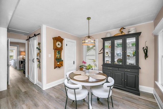 dining space featuring baseboards, a barn door, a wealth of natural light, and light wood-style floors