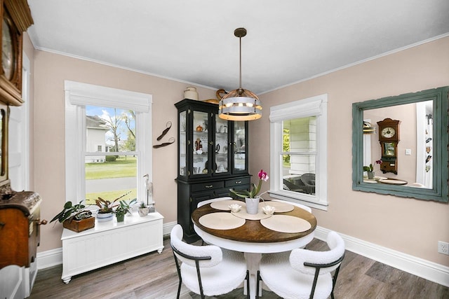 dining space with ornamental molding, a notable chandelier, plenty of natural light, and wood finished floors