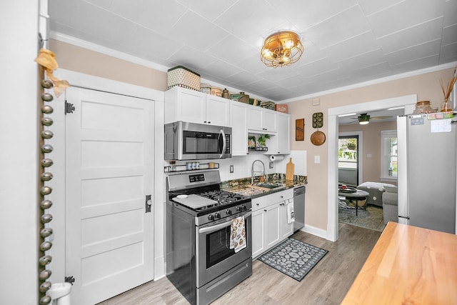 kitchen featuring crown molding, stainless steel appliances, white cabinetry, and a sink