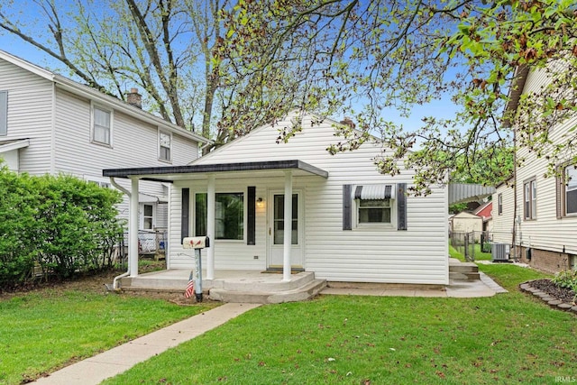 view of front of property with covered porch, cooling unit, and a front yard