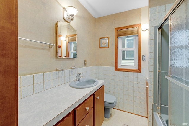 bathroom with toilet, tile walls, wainscoting, and vanity