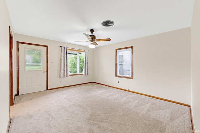 empty room with carpet floors, ceiling fan, visible vents, and baseboards