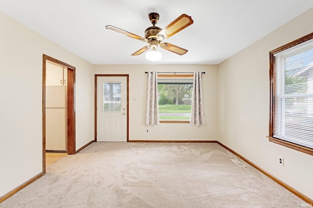 empty room with baseboards, visible vents, and light carpet