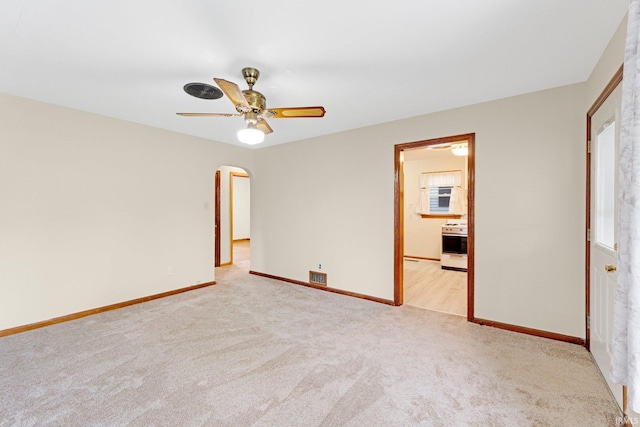 unfurnished bedroom with visible vents, light carpet, baseboards, ceiling fan, and arched walkways
