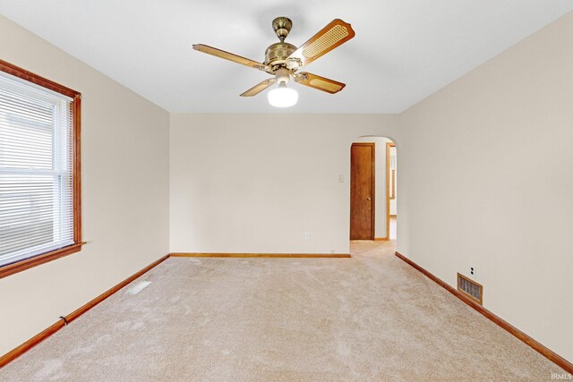 spare room with visible vents, carpet flooring, baseboards, ceiling fan, and arched walkways