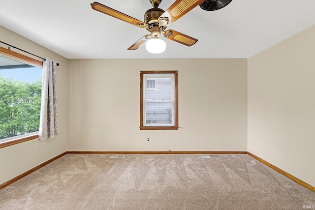 empty room with carpet floors, baseboards, ceiling fan, and visible vents