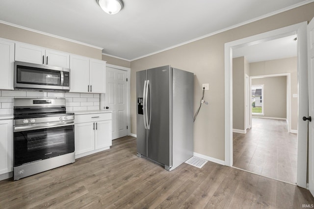 1743 Franklin Ave, Fort Wayne, IN 46808 - kitchen featuring white cabinetry, light countertops, ornamental molding, stainless steel appliances, and light wood-style flooring