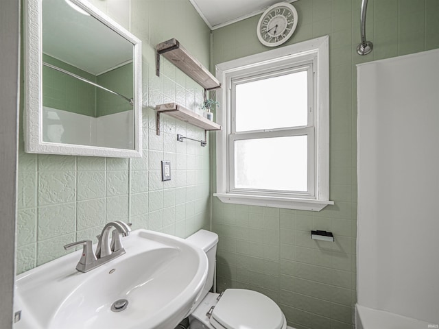 bathroom with a sink, tile walls, toilet, and a healthy amount of sunlight