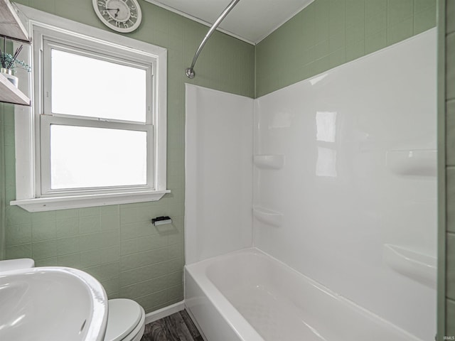 full bath with a sink, shower / bathtub combination, toilet, and wood finished floors