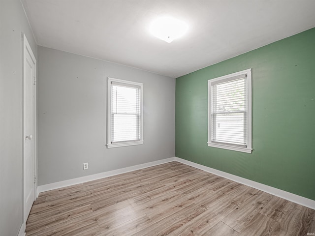 empty room with a healthy amount of sunlight, baseboards, and light wood-style floors