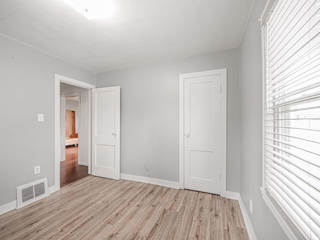unfurnished bedroom featuring baseboards, light wood-style flooring, and visible vents