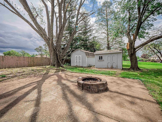 view of patio / terrace featuring an outdoor structure, a fire pit, fence, and a storage shed