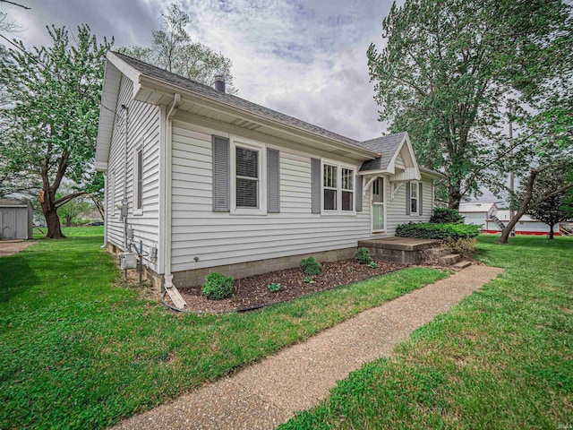 view of front of home featuring a shingled roof and a front yard