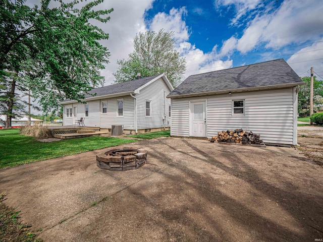 rear view of house with an outdoor structure, a fire pit, central AC, and a patio area