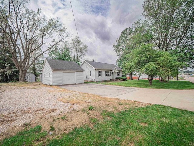 view of front of home with a detached garage, a shed, a front yard, an outbuilding, and driveway