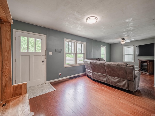 living room with ceiling fan, a fireplace, hardwood / wood-style floors, baseboards, and visible vents