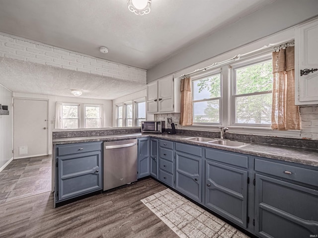 kitchen with stainless steel appliances, dark countertops, a sink, and a peninsula