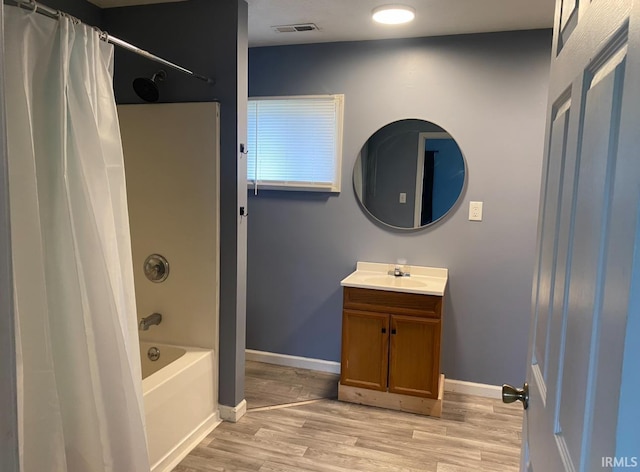 full bath featuring visible vents, vanity, wood finished floors, baseboards, and shower / tub combo
