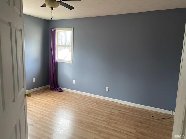 empty room with baseboards, ceiling fan, and light wood-style flooring