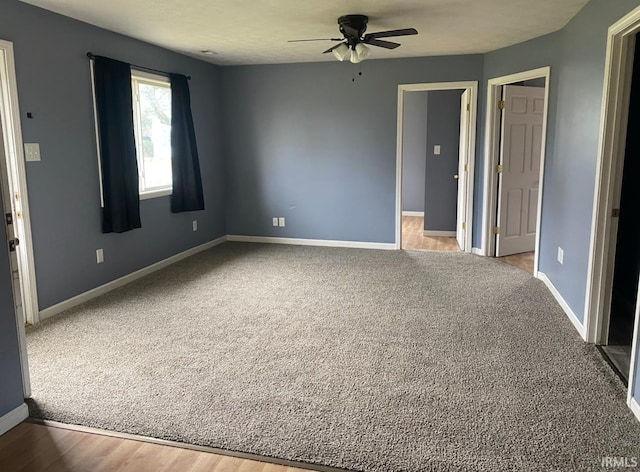 carpeted empty room featuring a ceiling fan and baseboards