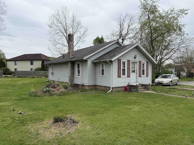 view of front facade featuring fence, a chimney, a shingled roof, and a front yard