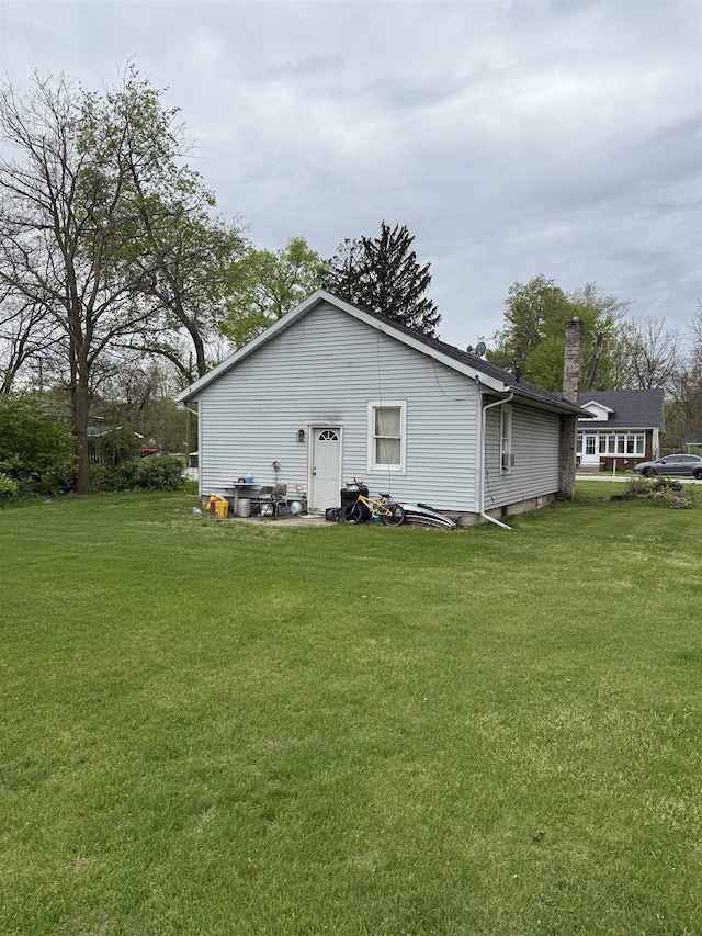 back of house featuring a yard and a chimney