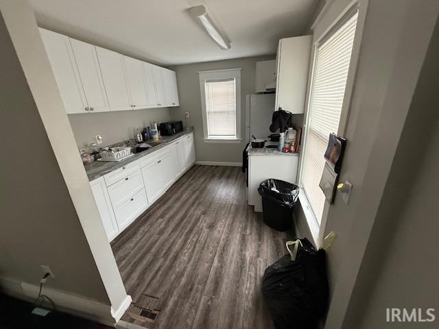 kitchen with freestanding refrigerator, dark wood-style flooring, baseboards, white cabinets, and a sink