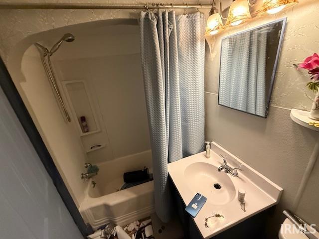 bathroom with vanity, a textured wall, toilet, and shower / bathtub combination with curtain