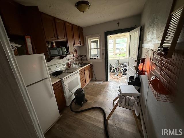 kitchen featuring light countertops, light wood-style flooring, and white appliances