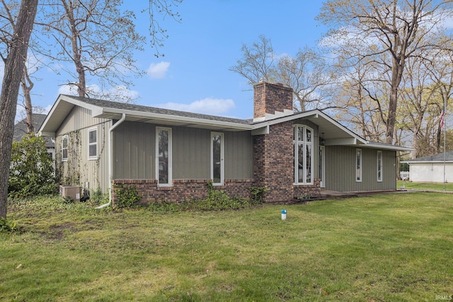 exterior space featuring brick siding, a chimney, central AC unit, and a front lawn