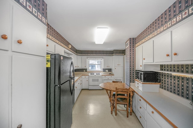 kitchen featuring white cabinets, white gas range oven, light countertops, freestanding refrigerator, and stainless steel microwave
