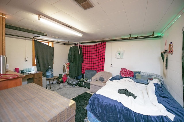 bedroom featuring concrete block wall and visible vents