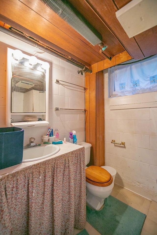 bathroom featuring toilet and concrete block wall