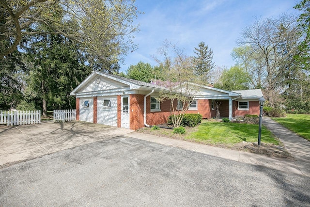 view of front of house with fence, a front yard, a chimney, brick siding, and driveway
