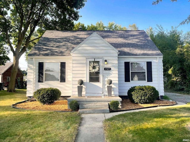 bungalow-style home with a shingled roof and a front yard