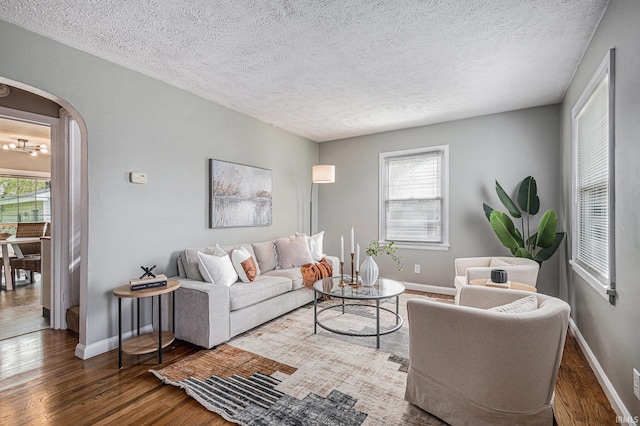living room with baseboards, arched walkways, a textured ceiling, and wood finished floors