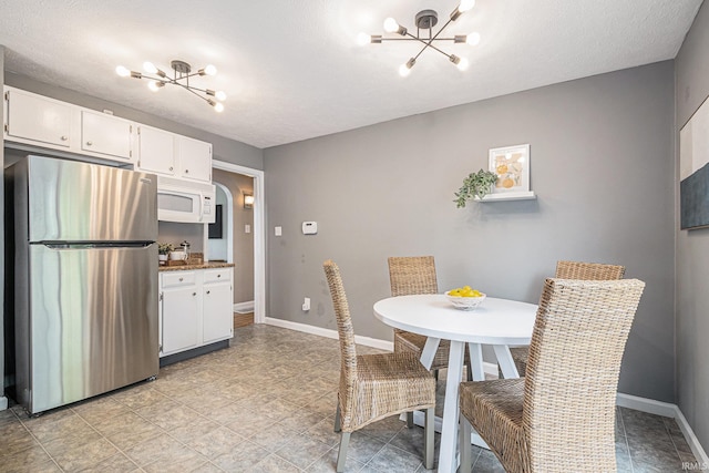dining area featuring light tile patterned floors, baseboards, and a notable chandelier