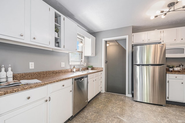 kitchen featuring open shelves, dark countertops, white cabinetry, a sink, and appliances with stainless steel finishes