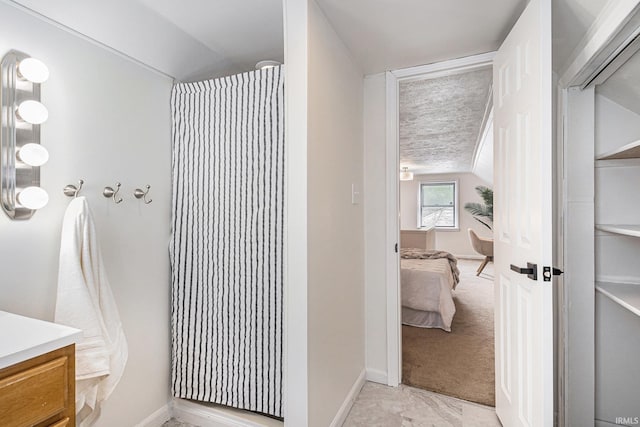 bathroom with vanity, connected bathroom, baseboards, and lofted ceiling