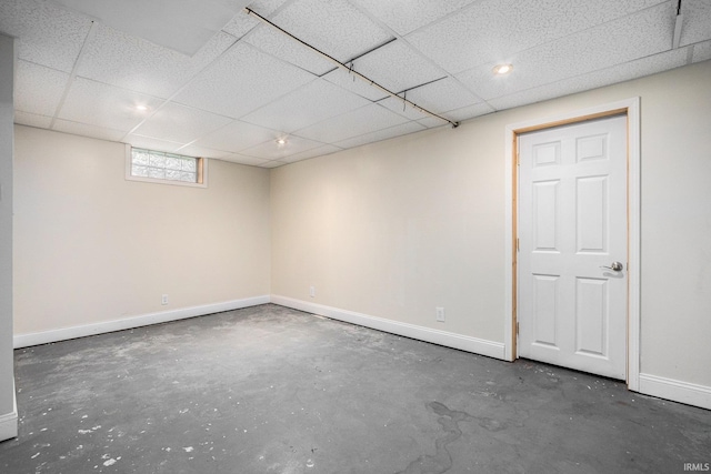 basement with baseboards and a drop ceiling