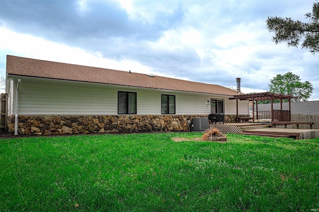 back of property with a lawn, a fire pit, a pergola, and stone siding