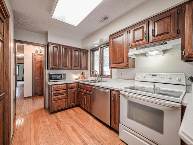 kitchen featuring under cabinet range hood, stainless steel appliances, a sink, and light countertops