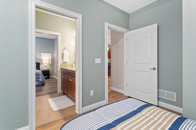 54637 Burdette St Unit 2, South Bend, IN 46637 - bedroom with light wood-style floors, baseboards, ensuite bath, and visible vents