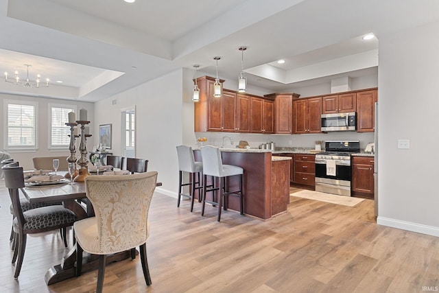 54637 Burdette St Unit 2, South Bend, IN 46637 - kitchen featuring appliances with stainless steel finishes, a breakfast bar area, a tray ceiling, and light wood-style flooring