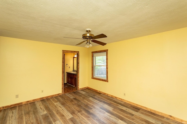 unfurnished room featuring baseboards, a ceiling fan, dark wood-style floors, and a textured ceiling
