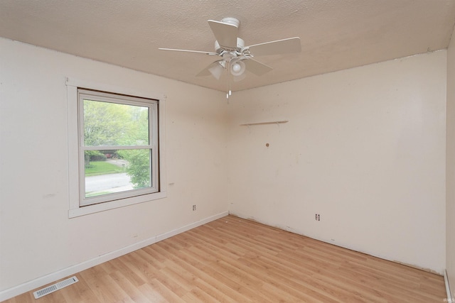empty room featuring visible vents, a ceiling fan, a textured ceiling, and light wood-type flooring