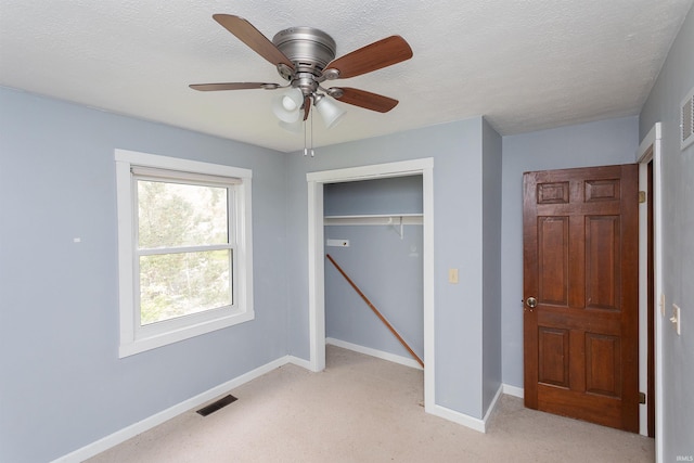 unfurnished bedroom with visible vents, a closet, baseboards, light colored carpet, and a ceiling fan