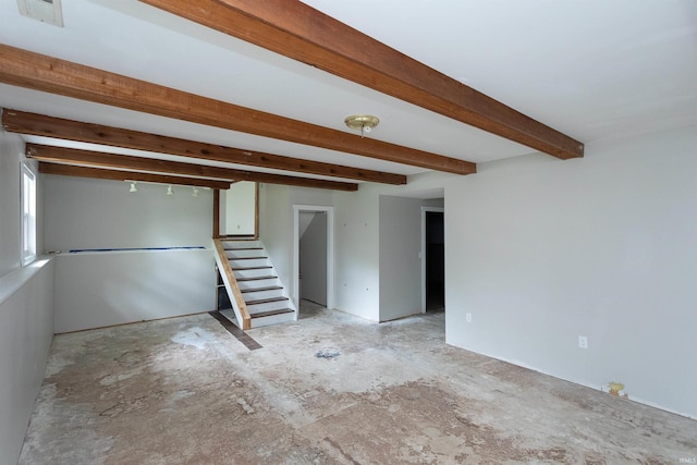 empty room featuring beamed ceiling, visible vents, and stairway