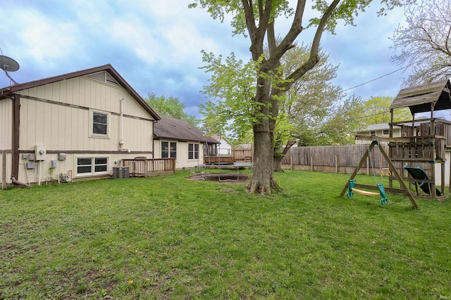 view of yard with a fenced backyard, central AC unit, a trampoline, and a playground
