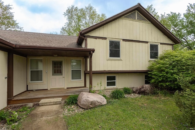 split level home with a shingled roof, covered porch, and a front yard